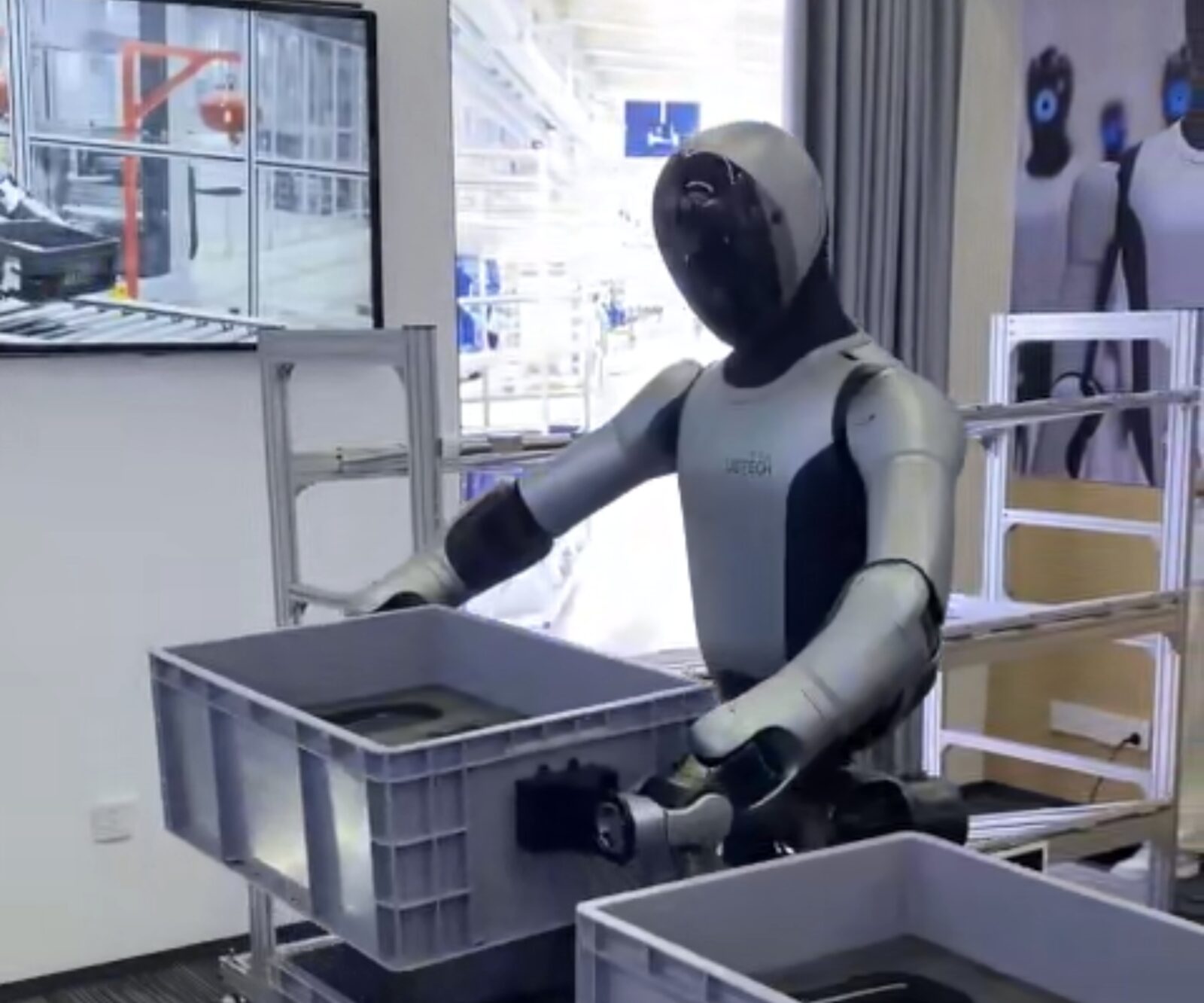 Humanoid robot moving plastic crates between racks in a Shenzhen facility.